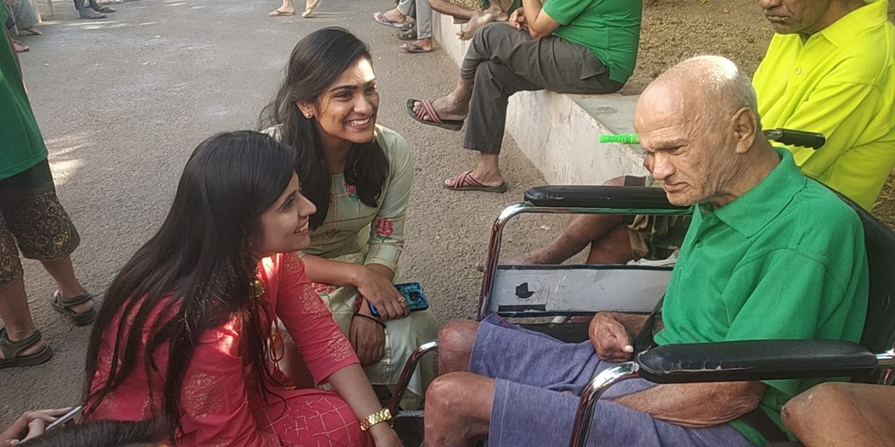 Two volunteers speaking with a senior resident in a wheelchair